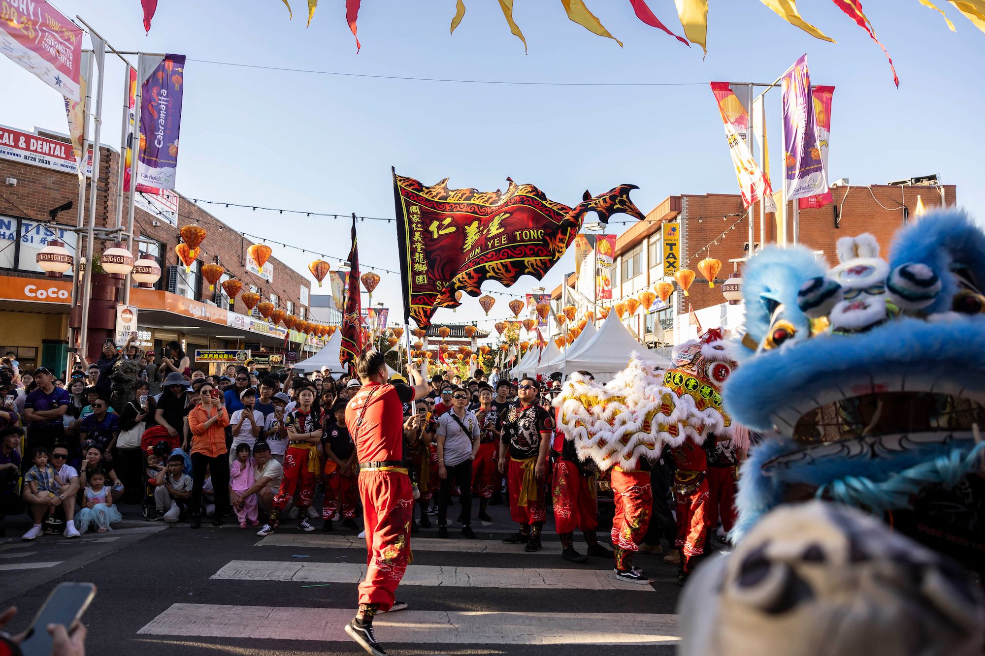 A lion dancer carrying a flag through the festival crowd